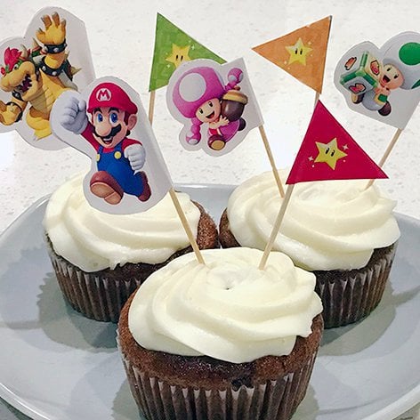 Photograph of several Mario Party: Star Rush flag picks lodged into cupcakes