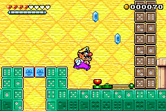 Screenshot of Wario about to press a button to break some domino blocks, from Wario Land 4.
