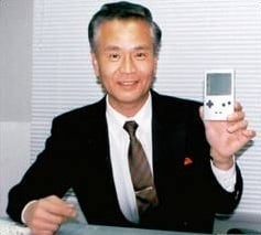 Gunpei Yokoi holding a gray Game Boy Pocket.