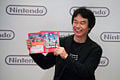 Shigeru Miyamoto showing the New Super Mario Bros. Wii cover.