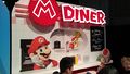 The Nintendo Switch being demoed in Multiplayer mode in a Mario-themed diner setting.