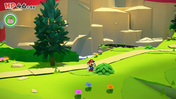 Mario standing near a bush containing a Small Bag of Confetti in Picnic Road of The Origami King.