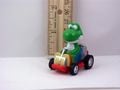 A figurine of Yoshi from from Super Mario Kart driving his kart