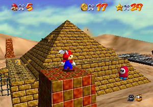 Mario stands on a pillar in Shifting Sand Land.