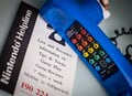 A different view of the blue variant of this telephone, shown here alongside a flyer for the Nintendo Helpline