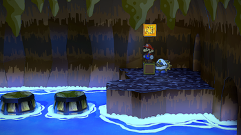 Mario next to the Shine Sprite in the floating barrel room of Pirate's Grotto in the remake of the Paper Mario: The Thousand-Year Door for the Nintendo Switch.