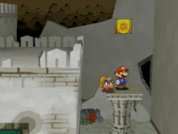 Mario next to the Shine Sprite on the roof of the rightmost column in the center room of level 1 of Rogueport Sewer in Paper Mario: The Thousand-Year Door.