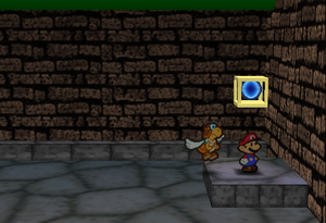 Mario standing next to the Super Block to the east of the west area entrance in Toad Town Tunnels in Paper Mario.