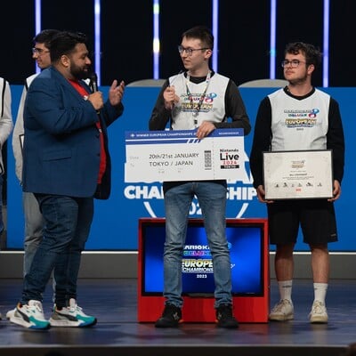 Photograph at the end of the Mario Kart 8 Deluxe European Championship 2023. Pictured is tournament host Nimmz (left) with players Mario (behind Nimmz), Thomas (center) and ᴍω clement. Thomas, who won the tournament, holds their boarding pass to the Nintendo Live 2024 event, where the Mario Kart 8 Deluxe World Championship 2024 was going to take place before the event's cancellation.