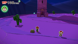 Mario standing near a rock containing a Small Bag of Confetti in Scorching Sandpaper Far West of The Origami King.