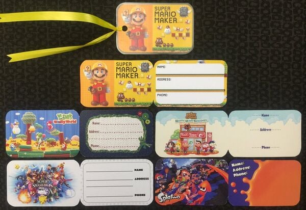 Photograph of several backpack tags branded with various Wii U games, such as Super Mario Maker, Yoshi's Woolly World, Animal Crossing: Happy Home Designer, Super Smash Bros. for Wii U, and Splatoon