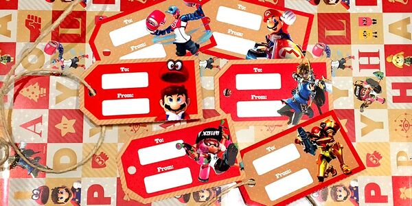 Photograph of several printed holiday gift tags featuring Nintendo games such as Super Mario Odyssey, Splatoon 2, The Legend of Zelda: Breath of the Wild, Metroid: Samus Returns, ARMS, and Mario Kart 8 Deluxe