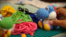 Screenshot of the first scene in episode 1 of Yoshi's Woolly World: Adventure Guide, the scene has Light-blue Yoshi, along with Yoshi, standing next to a pile of yarn