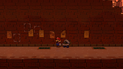 Mario near the poster containing a Super Mushroom in Riverside Station of Paper Mario: The Thousand-Year Door for Nintendo Switch.