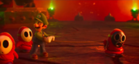 A troop of Shy Guys bring Luigi before Bowser for interrogation and eventual imprisonment.