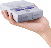 Hand holding small SNES as scale