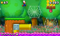 Mario, jumping towards a cobweb, which is next to a ! Switch, and a Yellow Pipe.