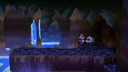Mario near 5 Coins hidden behind the elevated ground in the east of the area with the partially sunken ship in Pirate's Grotto of Paper Mario: The Thousand-Year Door for Nintendo Switch.
