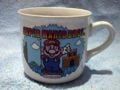 A mug labeled Super Mario Bros. above Mario, featuring the end of the overworld as the background