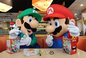 Photograph of Mario and Luigi performers posing with Mario Kart 8-themed Happy Meals inside a McDonald's restaurant in Los Angeles, California.