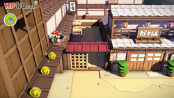 Mario standing near 3 Coins in Shogun Studios of The Origami King.