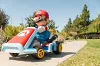 Photograph of a Mario plushy lying in a toy Standard Kart in an open space. The image was originally posted by Nintendo on social media websites.