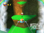 Tiptup flies to the Golden Balloon on a grassy ledge to the left of Wizpig's stone head in Diddy Kong Racing.