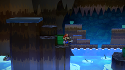Mario near 5 Coins hidden behind the elevated ground with the Plane Mode panel in the area where Toad sailors, Frankie and Francessca were trapped in Pirate's Grotto of Paper Mario: The Thousand-Year Door for Nintendo Switch.