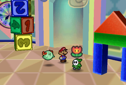Mario finding Fire Flower held by a green Shy Guy in Shy Guy's Toy Box of Paper Mario.