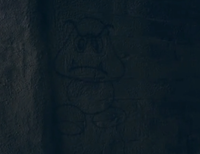 A screenshot from the movie 2025 - The World enslaved by a Virus, featuring some dimly-lit (in source) Goomba graffiti.