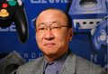 Tatsumi Kimishima in front of a Nintendo GameCube poster