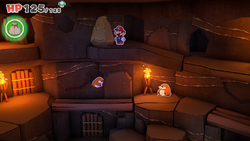 Mario standing near a rock containing a Monty mole who gives Mario a 100-Coin in Breezy Tunnel of The Origami King.