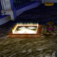 Wario about to enter a wooden trapdoor in Wario World