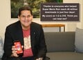 Reggie holding a phone with Super Mario Run on it