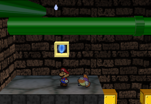 Mario standing next to the Super Block to the left of the Dark Koopa gate in Toad Town Tunnels in Paper Mario.