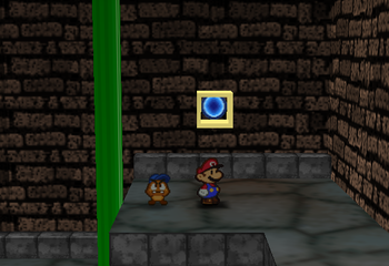 Mario standing next to the Super Block deep in the west area entrance in Toad Town Tunnels in Paper Mario.