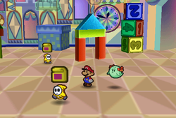 Mario finding Cake Mixes held by two yellow Shy Guys in Shy Guy's Toy Box of Paper Mario.