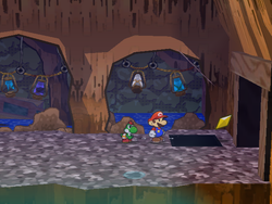 Mario getting the Star Piece under a hidden panel in the waterfall room of the Pirate's Grotto in Paper Mario: The Thousand-Year Door.